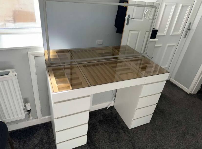 Kaptafel met glazen blad en grote spiegel in een lichte kamer
